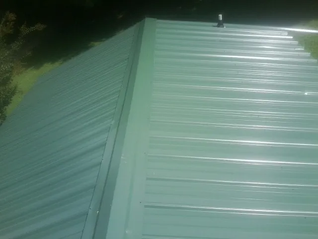 New green metal panels meeting at the ridge of a roof — Flat Roof Repair work by our crew in Wakefield